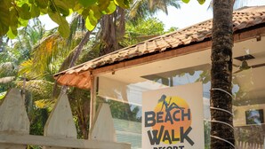 A sign for Beach Walk Resort with a palm tree and a fence in the background. - BeachWalk By FeatherTouch Hotels Resorts (Morjim)
