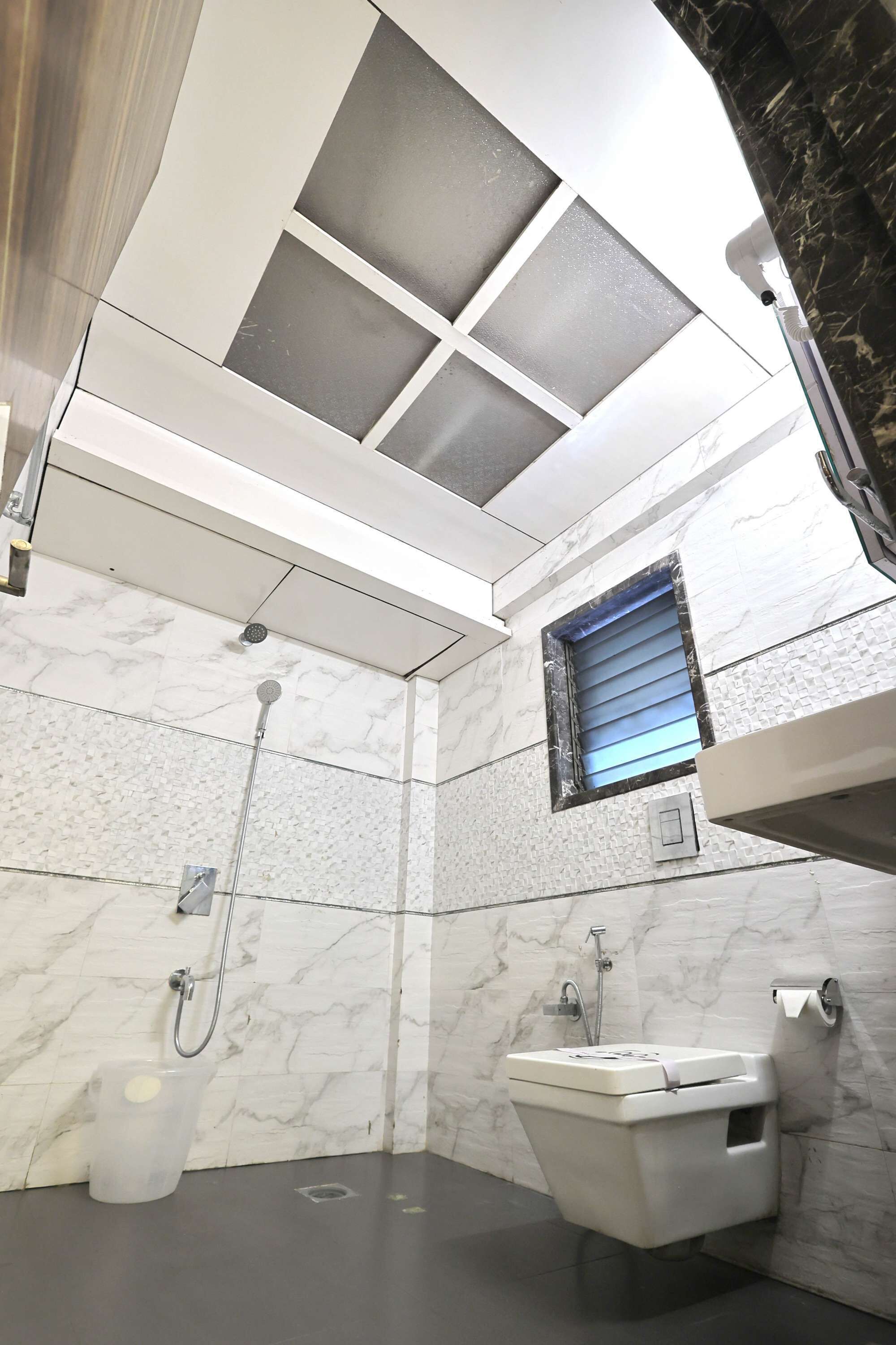 A modern bathroom with a shower, toilet, and a small window.