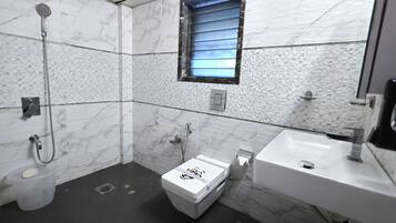 A bathroom with a shower, toilet, and sink, featuring marble walls and a small window.