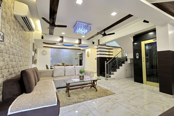 A modern living room with a sofa, coffee table, and a staircase leading to an upper level. - Entire 4 Bedroom Villa (Mumbai)