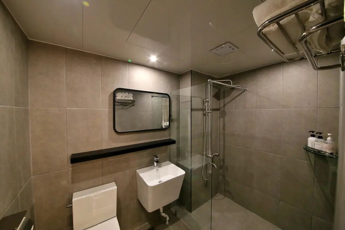 Un bagno moderno con cabina doccia in vetro, un lavandino bianco e uno specchio sopra.