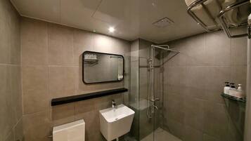 Un bagno moderno con cabina doccia in vetro, un lavandino bianco e uno specchio sopra.