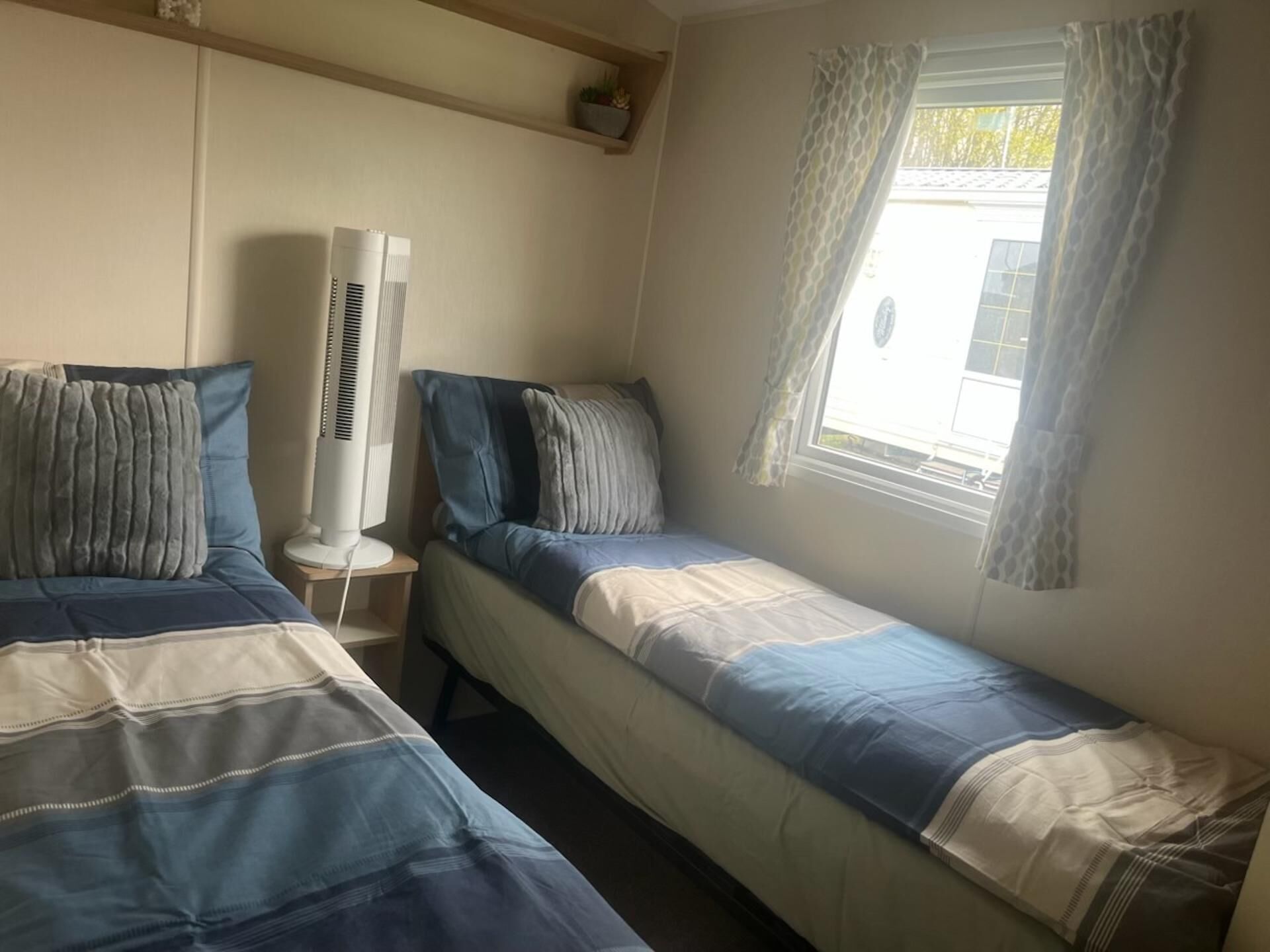 Un dormitorio con dos camas, un calentador portátil y una ventana con cortinas.