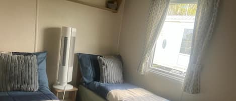 Un dormitorio con dos camas, un calentador portátil y una ventana con cortinas.