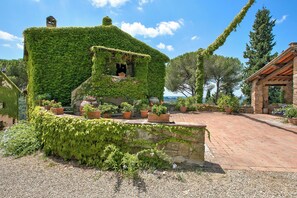 A house with ivy-covered walls, a stone foundation, and a garden with potted plants.
