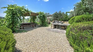 A garden patio with a pergola, a stone barbecue area, and a gravel path. - Relaxing Tuscan Terrazza Near Florence 4shared Pool (Impruneta)