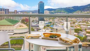 Una mesa con comida y dos vasos de agua, con vistas a un paisaje urbano que incluye edificios y montañas.