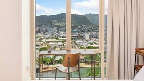 Una habitación con un amplio ventanal que ofrece vistas a la ciudad, una silla de madera y una mesa.