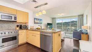 Una cocina moderna con horno empotrado, microondas y lavavajillas. Hay una isla grande con un fregadero y un área de comedor con vista a la ciudad.
