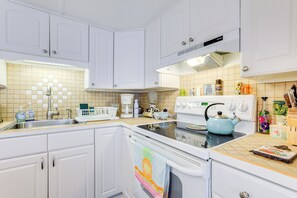 Een keuken met witte kastjes, een fornuis en een spoelbak.