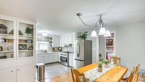 A modern kitchen with white cabinets, a wooden dining table, and a stainless steel refrigerator. - 4 Mi to Dtwn: Goodlettsville Getaway w/ Yard (Goodlettsville)