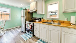 A kitchen with white cabinets, a stainless steel refrigerator, a stove, and a wooden countertop. - Walk to Pier & Dining: Central Rockport Cottage (Rockport)
