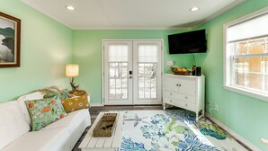 A room with a white sofa, a patterned rug, a television mounted on the wall, and a white dresser. - Walk to Pier & Dining: Central Rockport Cottage (Rockport)