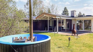 Una casa moderna con patio coperto, vasca idromassaggio e camino.