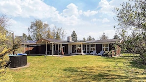 Una casa moderna con patio coperto, un ampio prato e un impianto solare per scaldare l'acqua.