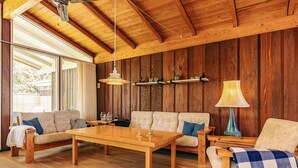 Un'accogliente stanza con pareti e pavimenti in legno, un divano, un tavolo da pranzo e una lampada.