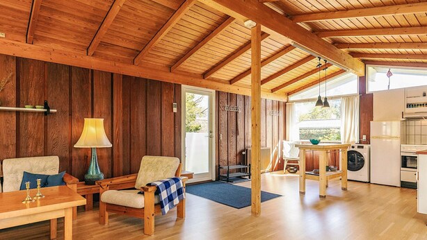 Un'ampia zona giorno con pavimenti in legno e soffitto alto, caratterizzata da un divano, un tavolo e una lampada.