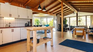 Un'ampia cucina con travi in legno, un'area pranzo con tavolo e sedie, e un accogliente soggiorno con divano e televisione.
