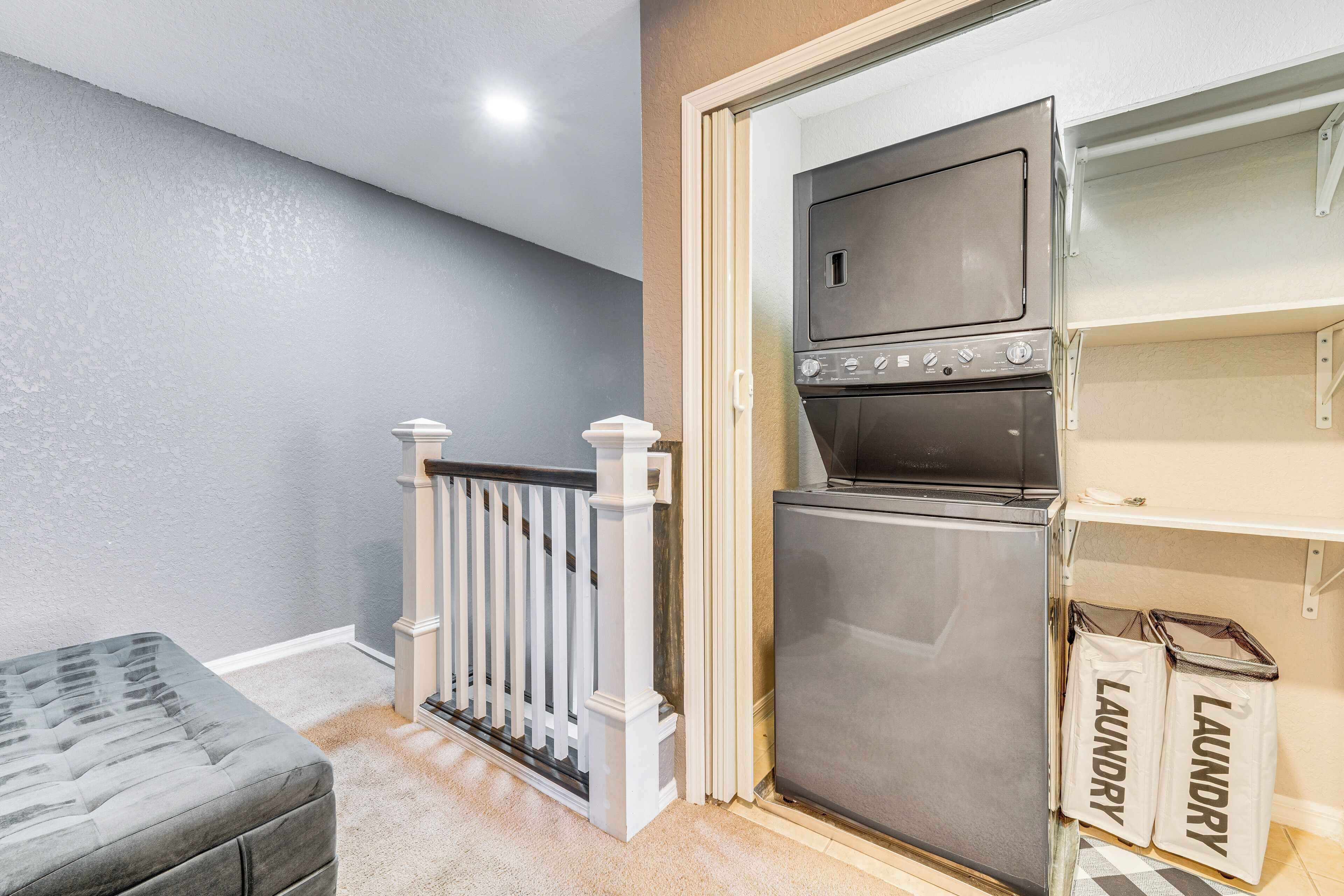 A laundry room with a washer and dryer, a small seating area, and a white railing.