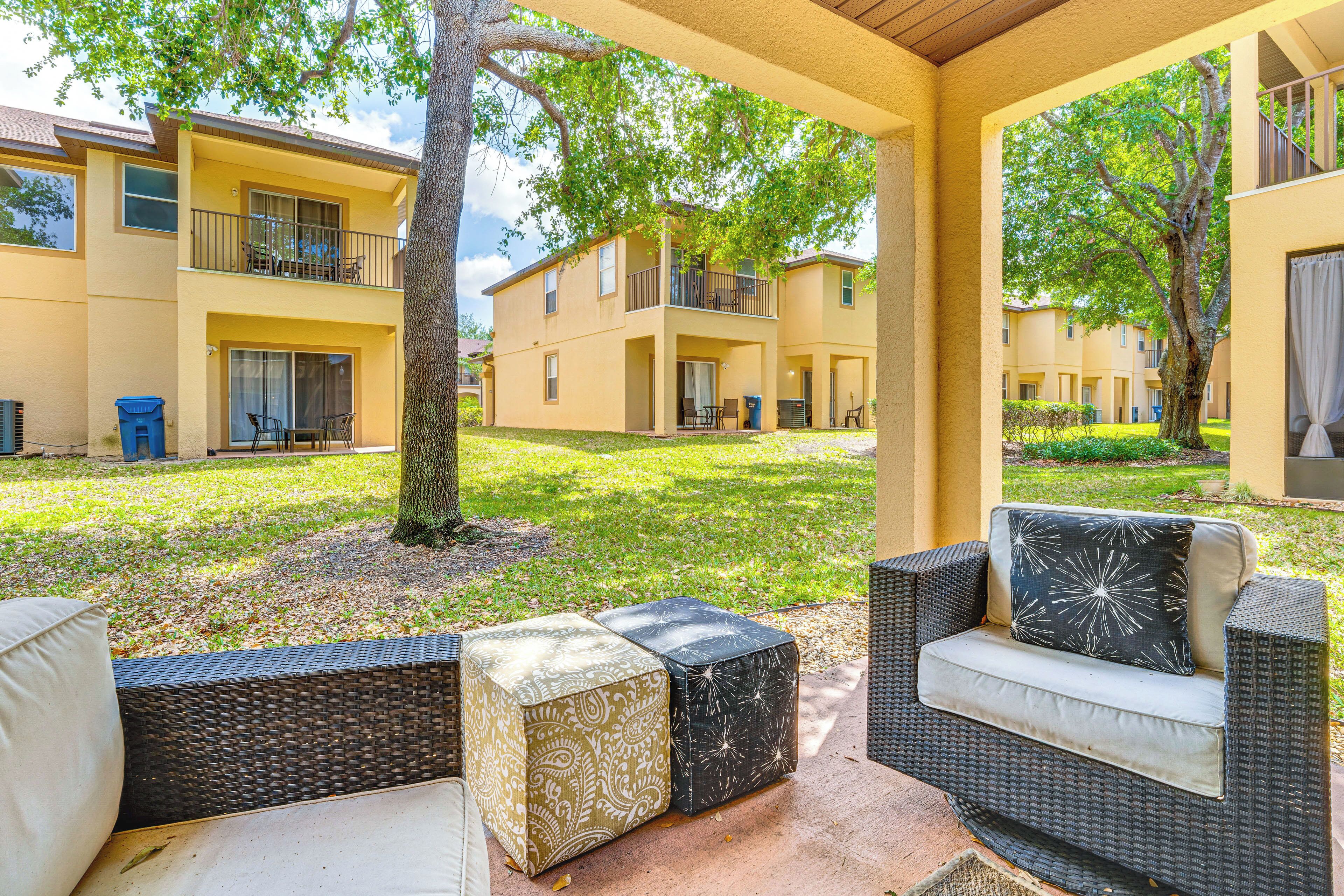 A covered outdoor seating area with wicker furniture and a view of a residential building.