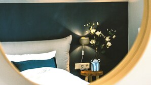 Ein Schlafzimmer mit Bett, Nachttisch, Lampe und einer Vase mit Blumen.