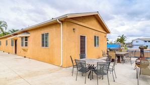 Un bâtiment doté d’un toit plat, d’un patio avec une table et des chaises, et d’un barbecue.