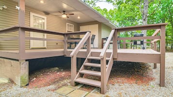Una terraza de madera con una escalera que lleva a un espacio cubierto con una mesa y sillas.