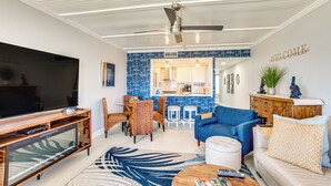 A modern living room with a flat-screen TV, a blue sofa, and a coffee table. - Beach Access: Ocean-view Condo w/ Screened Balcony (Harbor Island)