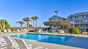A swimming pool with lounge chairs, palm trees, and a building with balconies. - Beach Access: Ocean-view Condo w/ Screened Balcony (Harbor Island)