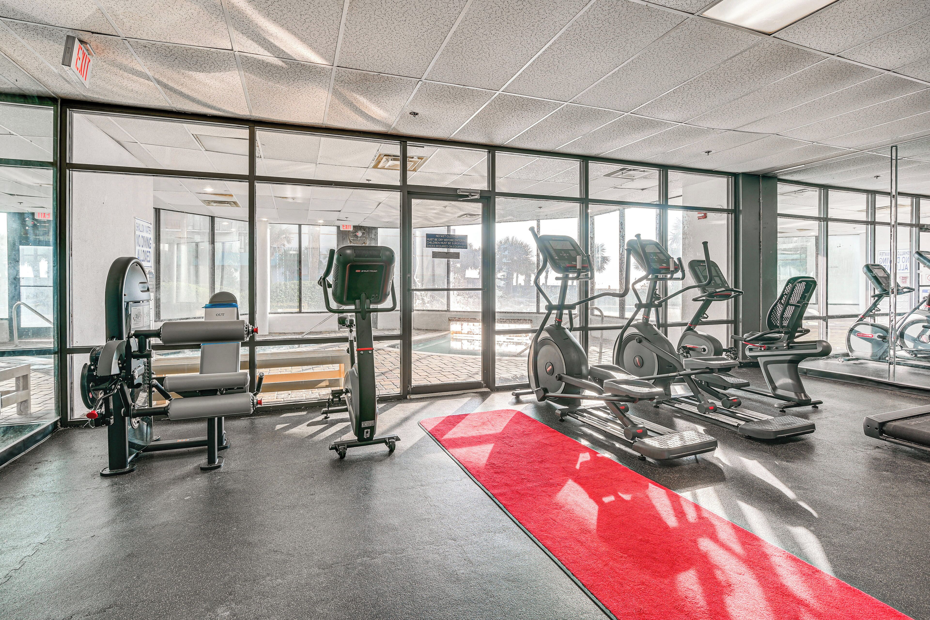 A gym with cardio machines, weight machines, and a red carpet.