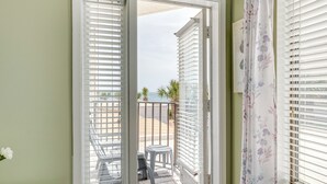 Een balkon met uitzicht op het strand, een tafeltje en een stoel.