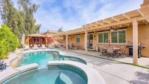 A pool area with a curved design, outdoor seating, and a pergola structure. - Gazebo + Putting Green: Serene Indio Getaway (Indio)