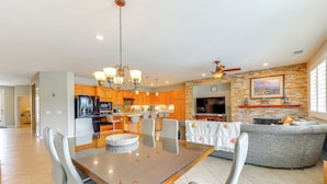 A spacious living area with a dining table, chairs, a sofa, and a kitchen in the background. - Gazebo + Putting Green: Serene Indio Getaway (Indio)