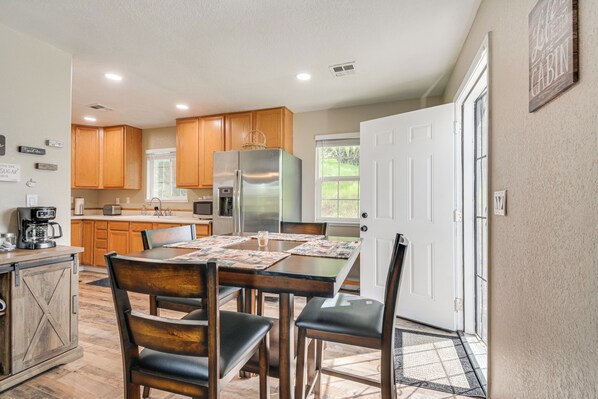 A modern kitchen with wooden cabinets, a stainless steel refrigerator, and a dining table with chairs.