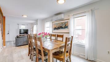 Un comedor con mesa y sillas de madera, un jarrón con flores y un cuadro en la pared.