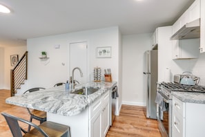 A modern kitchen with white cabinetry, a granite countertop, and stainless steel appliances.