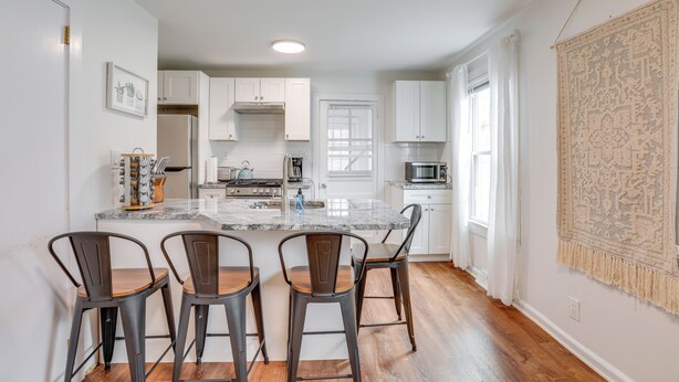 A kitchen with white cabinets, a marble countertop, and three stools. - Walkable Dtwn Townhome Near Campus & Palmer Square (Princeton)