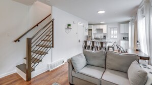 A modern living room with a staircase, a sofa, and a dining area. - Walkable Dtwn Townhome Near Campus & Palmer Square (Princeton)