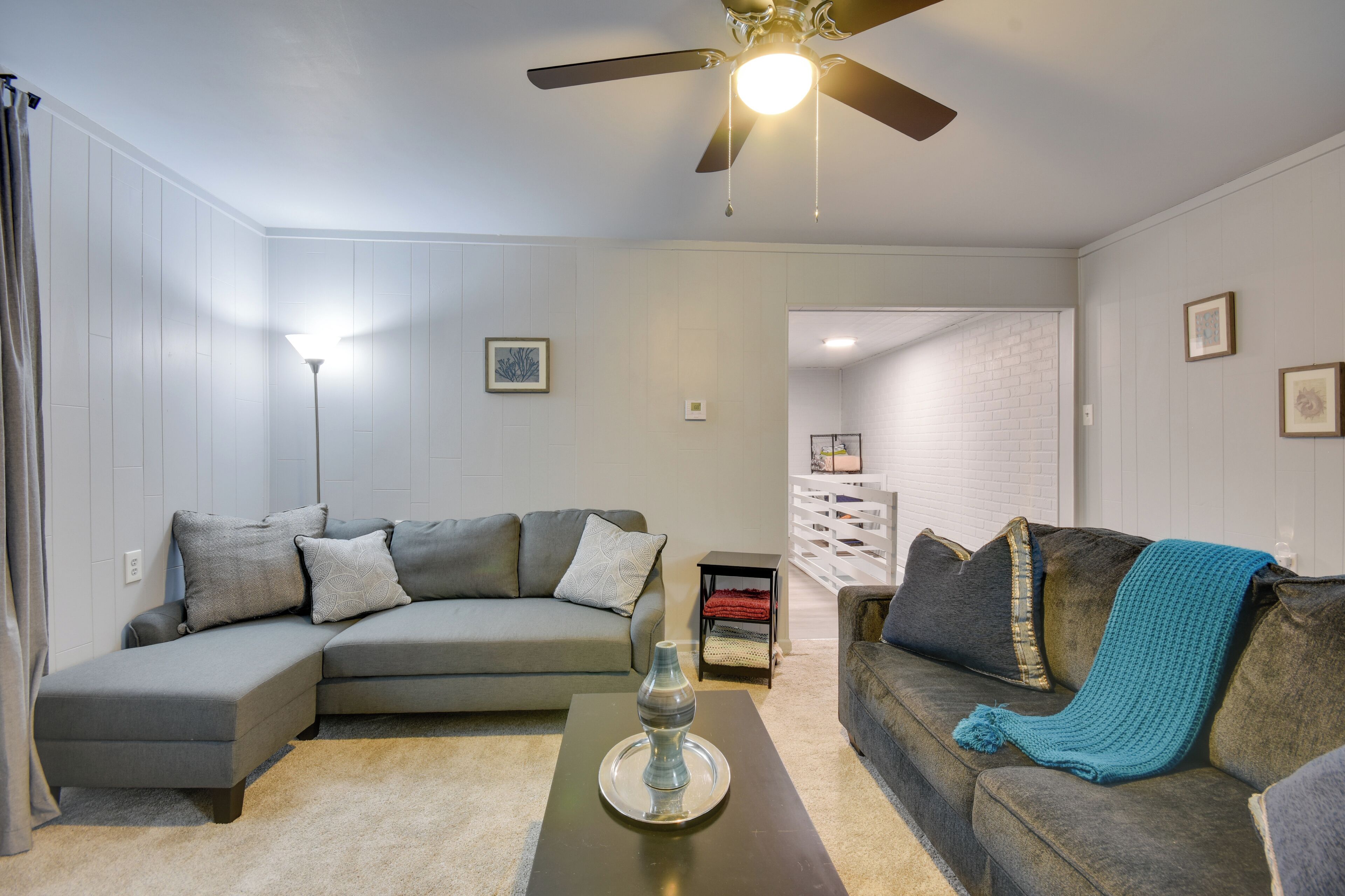 A living room with a sectional sofa, a coffee table, and a ceiling fan.