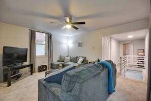 A living room with a television, sofa, and ceiling fan.