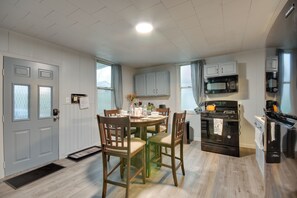 A modern kitchen with wooden cabinets, a dining table with chairs, a black stove, and a microwave.