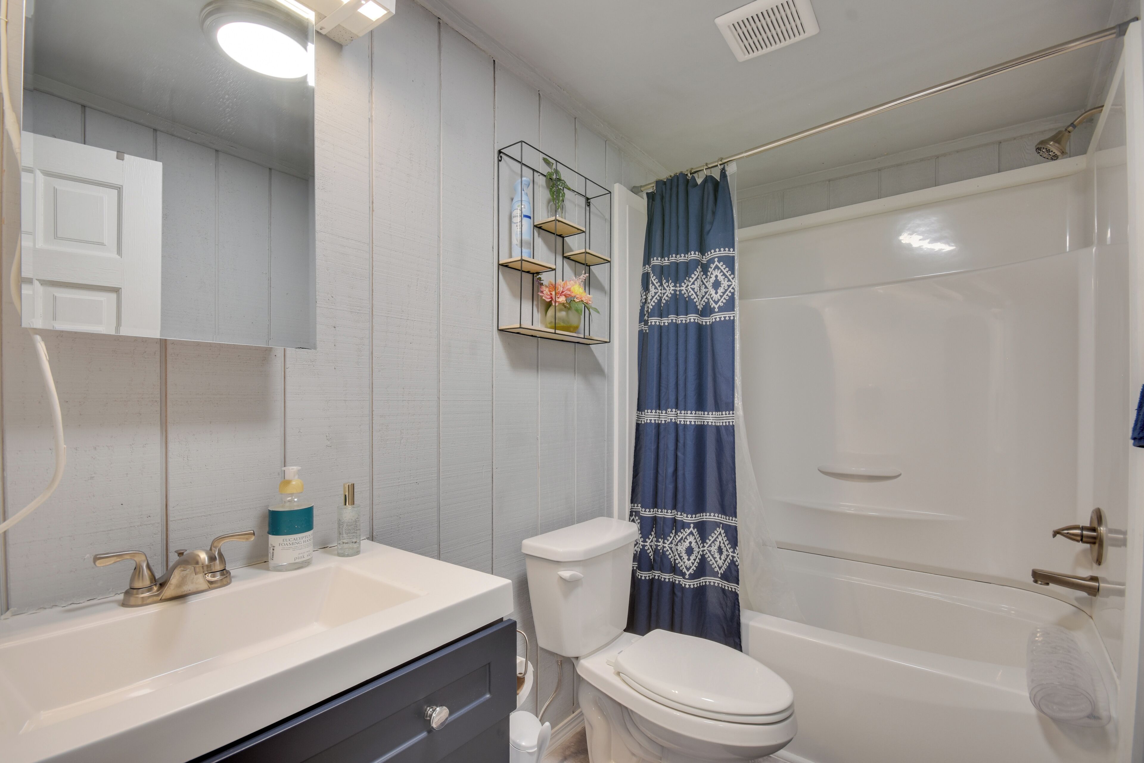 A bathroom with a white sink, a toilet, and a bathtub. There is a shower curtain with a geometric pattern.