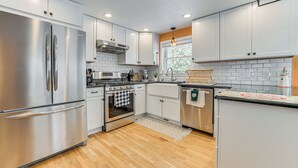 A modern kitchen with stainless steel appliances, white cabinets, and a wooden floor. - Walk to Lake Huron Beaches: Home w/ Fire Pit! (Rogers City)