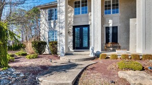 A two-story house with a stone facade, a front porch with steps, and a bench. - Theater & Game Room at Trenton Area Home (Jackson)
