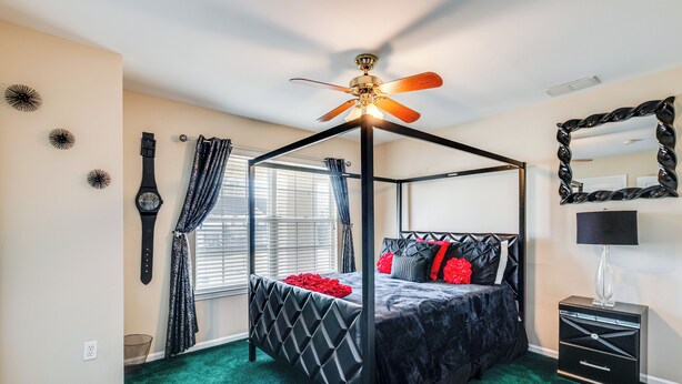 A four-poster bed with a black canopy, a ceiling fan, and a nightstand with a lamp. - Theater & Game Room at Trenton Area Home (Jackson)