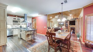 A spacious kitchen with wooden cabinets, a central island, and a dining area with a large table and chairs. - Private Dock: 'the River House' in Heber Springs! (Heber Springs)