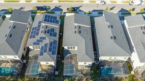 Ett bostadsområde med flera hus, där varje hus har ett solpanelssystem installerat på taket.