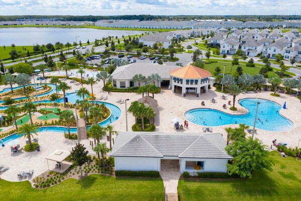 A resort with a large swimming pool, a golf course, and a view of a lake.