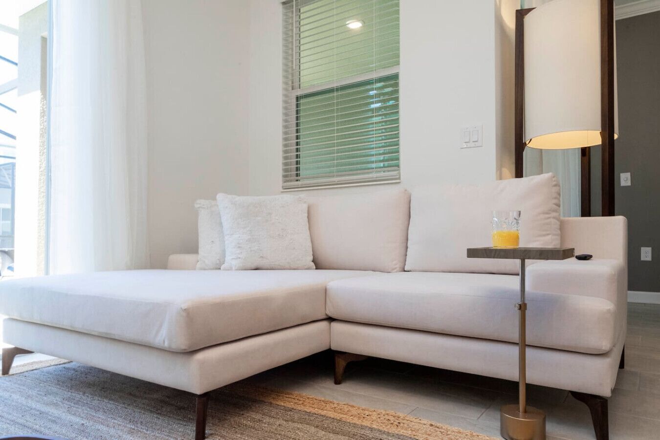 Uma sala de estar moderna com um sofá seccional, um abajur e uma mesinha de centro com um copo.