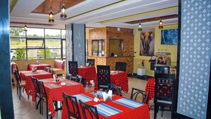 Un restaurant avec des nappes à carreaux rouges, des chaises noires et un mur en pierre.